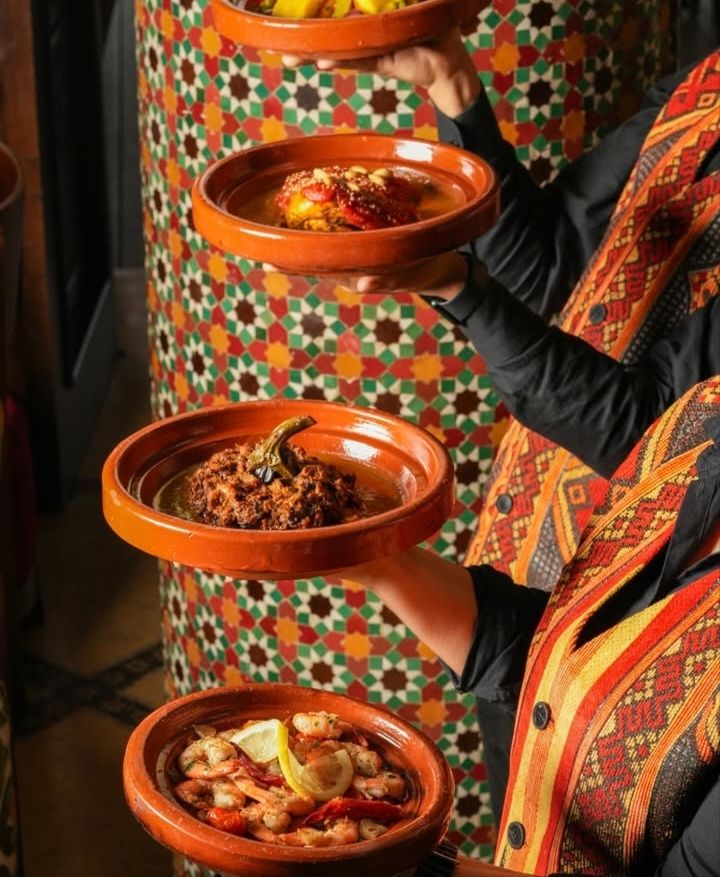 Waiter presenting a tower of tagines